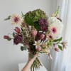 Handheld bouquet with hydrangeas, tulips, and daisy-like blooms in pink, white, and green