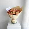 Bouquet of peach and pink roses wrapped in cream paper