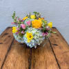 Mixed bouquet with yellow roses, pink tulips, and blue hydrangeas in a low container