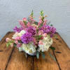 Purple and pink mixed bouquet with white hydrangeas in a low vase