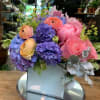 Colorful bouquet of pink, purple, and peach flowers in a white box