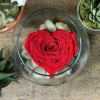 Red rose arranged in a heart shape inside a glass bowl with white stones