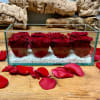 Red roses arranged in a clear rectangular glass box with white stones