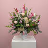 Mixed pastel bouquet in a frosted glass vase on a white pedestal