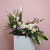 Large floral arrangement with white calla lilies and pale roses on a pedestal