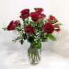 Red roses arranged in a clear glass vase with small white filler flowers.