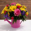 Bright mixed bouquet in a pink watering can vase