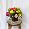 Colorful mixed bouquet in a dark square vase on a wooden stool