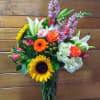 Mixed bouquet with sunflowers, roses, lilies, and hydrangeas in a glass vase