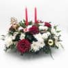 Red and white floral centerpiece with two red candles and gold holiday ornaments