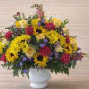 Mixed bouquet of yellow sunflowers, roses, and pink carnations in a white vase