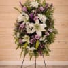 Standing floral wreath with white lilies, lavender roses, and purple accents