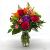 Mixed bouquet of roses, lilies, and purple flowers in a glass vase