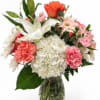 Mixed bouquet of lilies, roses, hydrangea, and carnations in a glass vase