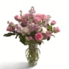 Pink roses and lilac flowers arranged in a clear glass vase