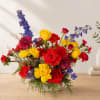 Colorful mixed bouquet in a white vase with red, yellow, blue, and pink flowers