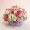 Round bouquet of pink and white roses with white blooms in a low container