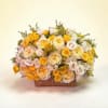 Bouquet of yellow, cream, and pale pink roses in a rectangular vase