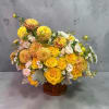 Yellow and peach floral arrangement in a wooden container