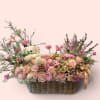 Pink rose basket arrangement with a plush bunny and ribbon