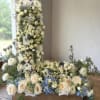 White floral cross arrangement with blue accents on a table