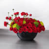 Red roses and green button mums arranged in a black bowl vase
