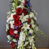 Standing floral spray with red, white, and blue flowers on a ribboned easel