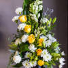 Tall floral arrangement with yellow roses, white blooms, and a black vase
