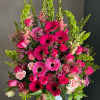Large pink and green floral arrangement in a white vase