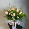 Peach roses in a glass vase with a pink ribbon bow