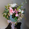 Pink and white mixed bouquet in a glass vase with a pink ribbon