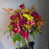 Bouquet of red roses, pink spray roses, and yellow mums in a glass vase
