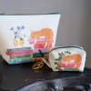 Two floral-print zip pouches with an orange cat and books