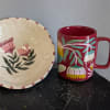 Decorative floral plate beside a red mug with painted flowers