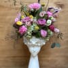 Pink and white floral arrangement in a white face vase