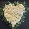 Heart-shaped white floral wreath with a ribbon reading "Beloved Mom"