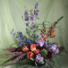 Tall mixed bouquet with orange roses and purple flowers in a black vase