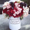 Red and pink roses with white orchids in a white hat box