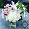Pink roses and white orchids arranged in a clear square vase