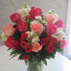 Bouquet of pink, red, and peach roses in a clear glass vase