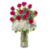 Red roses arranged with white hydrangeas in a clear glass vase