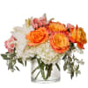 Orange and pink roses with white lilies and hydrangeas in a clear glass vase