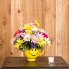 Colorful mixed bouquet in a yellow smiley-face mug vase