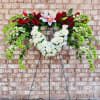 Standing floral wreath with red and white flowers on a metal easel