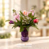 Pink and purple mixed bouquet in a purple glass vase