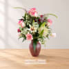 Pink roses and lilies arranged in a vase with white filler flowers