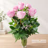 Pink roses arranged in a clear glass vase with greenery