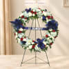 Floral memorial wreath with red, white, and blue flowers on a stand