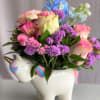 Pink and purple flowers arranged in a unicorn-shaped ceramic container
