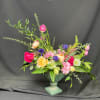 Mixed bouquet of pink, yellow, purple, and white flowers in a decorative urn vase